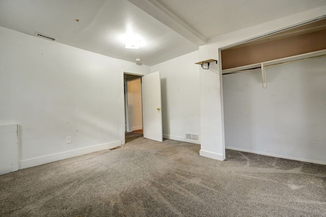 unfurnished bedroom featuring beamed ceiling, carpet floors, and a closet