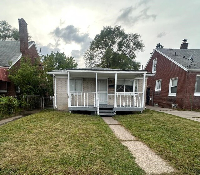 bungalow-style home featuring covered porch and a front yard