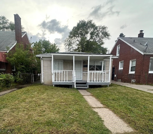 view of front facade featuring a porch, brick siding, and a front yard