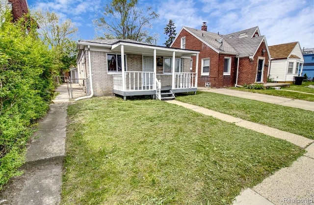 bungalow featuring covered porch, brick siding, and a front yard