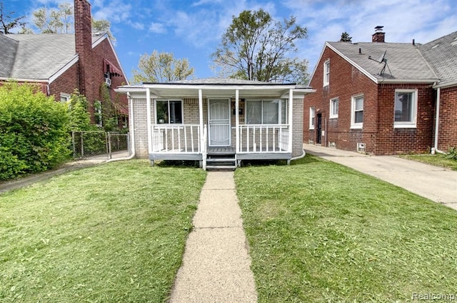bungalow-style home with covered porch, brick siding, and a front yard