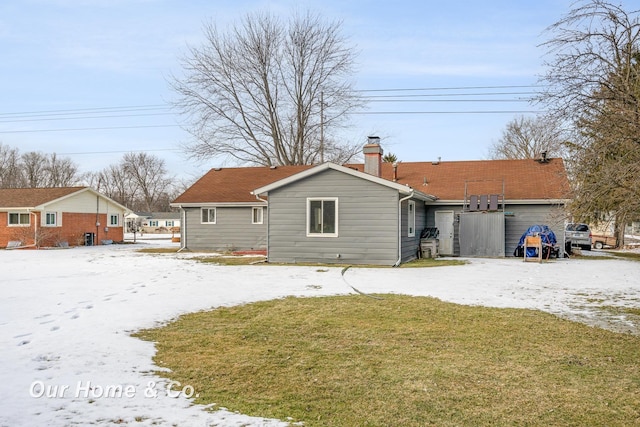 snow covered back of property with a lawn