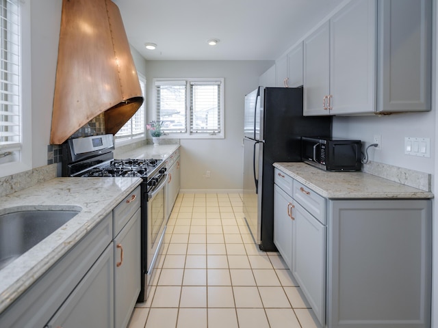 kitchen featuring light stone countertops, island exhaust hood, stainless steel range with gas cooktop, and light tile patterned floors