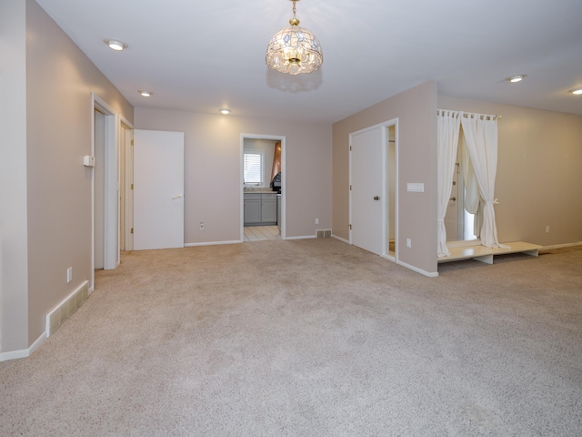 carpeted spare room with a chandelier