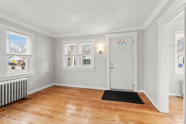 foyer entrance with radiator heating unit and light hardwood / wood-style flooring