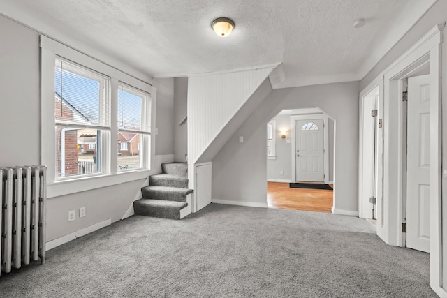 carpeted foyer entrance with radiator and a textured ceiling