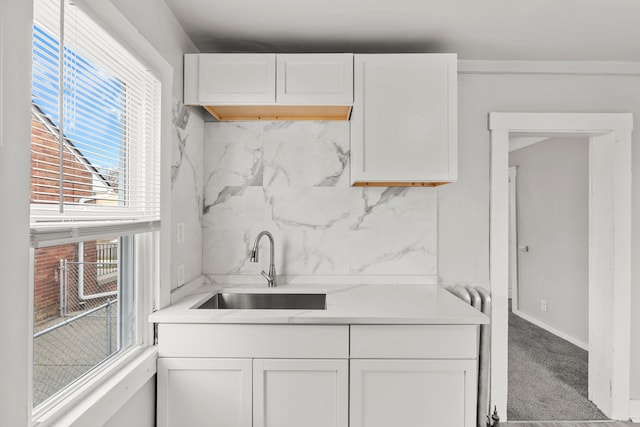 kitchen with carpet floors, white cabinetry, sink, and decorative backsplash