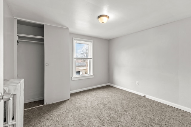 unfurnished bedroom featuring radiator, dark carpet, and a closet