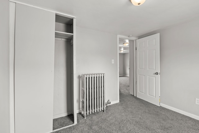 unfurnished bedroom with radiator heating unit, carpet flooring, and a closet