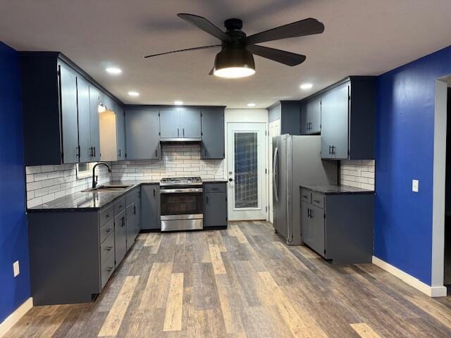 kitchen with dark wood-type flooring, sink, ceiling fan, stainless steel appliances, and backsplash