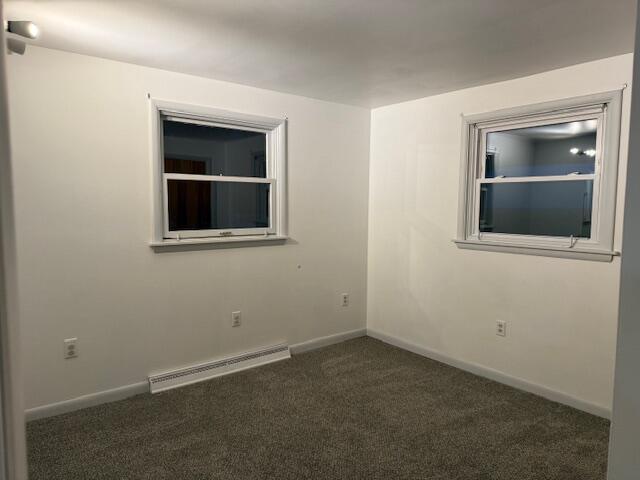 carpeted spare room featuring baseboard heating