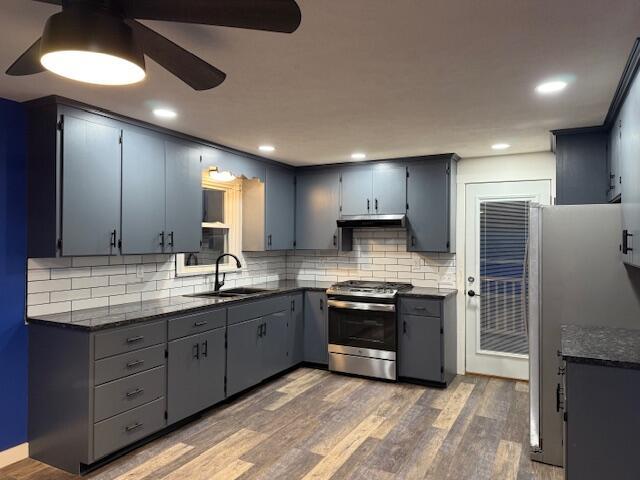 kitchen with appliances with stainless steel finishes, tasteful backsplash, sink, gray cabinetry, and dark wood-type flooring