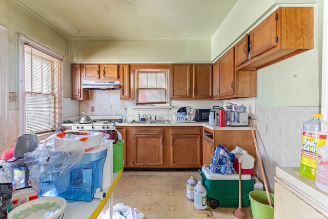 kitchen featuring brown cabinets, light countertops, and under cabinet range hood