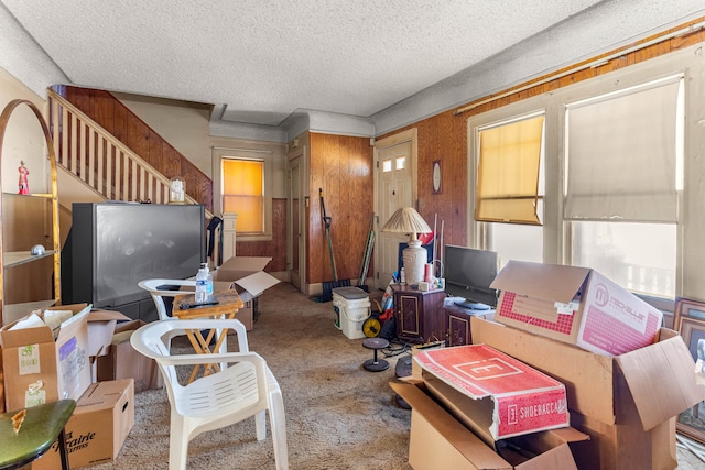 living area featuring stairway, light colored carpet, and a textured ceiling