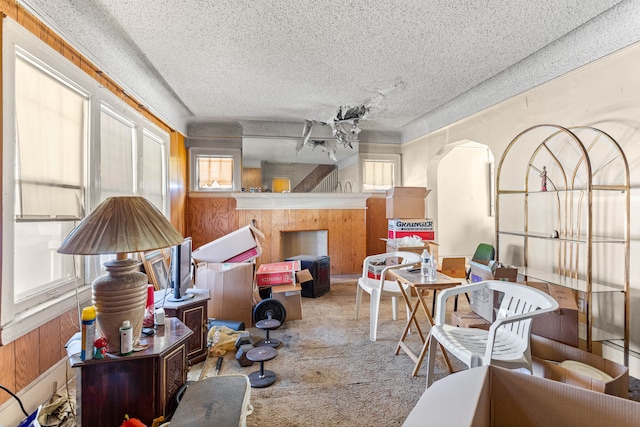 interior space featuring carpet floors, arched walkways, a wainscoted wall, a textured ceiling, and wooden walls