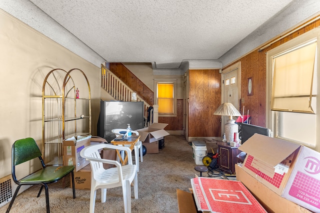 living area with light carpet, wood walls, and a textured ceiling