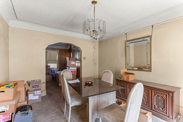 dining room featuring arched walkways, carpet flooring, a textured ceiling, and an inviting chandelier