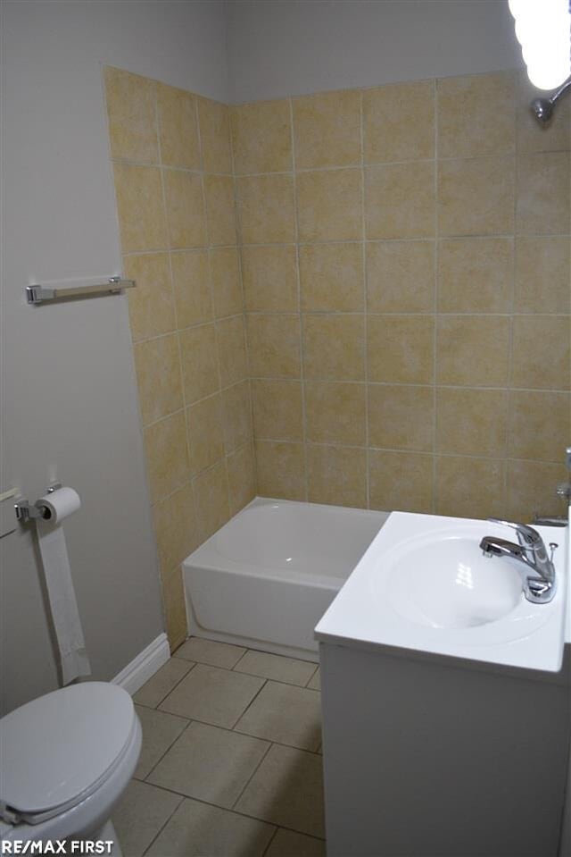 full bathroom featuring tile patterned flooring, vanity, tiled shower / bath combo, and toilet