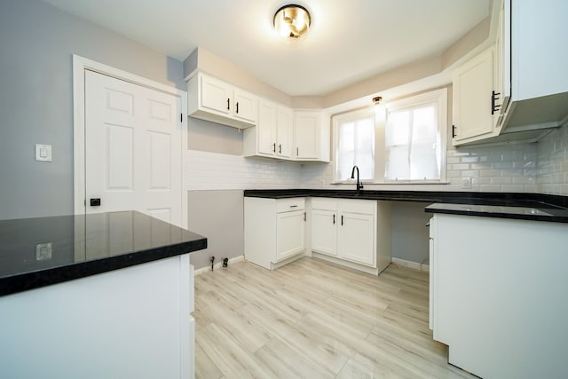 kitchen featuring light hardwood / wood-style flooring, sink, decorative backsplash, and white cabinets