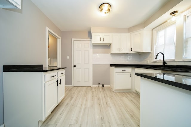 kitchen featuring white cabinetry, sink, tasteful backsplash, and light wood-type flooring