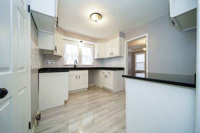 kitchen with tasteful backsplash, sink, light hardwood / wood-style flooring, and white cabinets