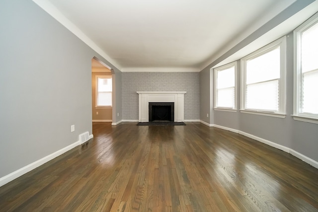 unfurnished living room featuring dark hardwood / wood-style floors and a healthy amount of sunlight