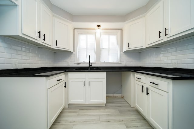 kitchen with sink, light hardwood / wood-style flooring, white cabinets, and decorative backsplash