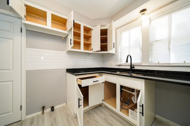 kitchen featuring white cabinetry, sink, backsplash, and light hardwood / wood-style floors