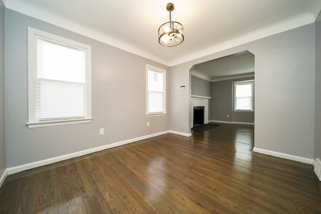 unfurnished living room with an inviting chandelier, dark wood-type flooring, and a fireplace