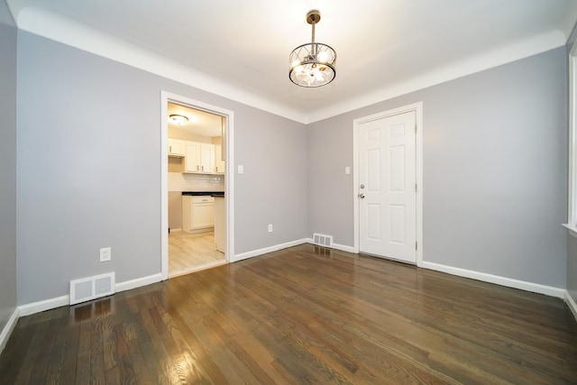 unfurnished room with a chandelier and dark hardwood / wood-style flooring