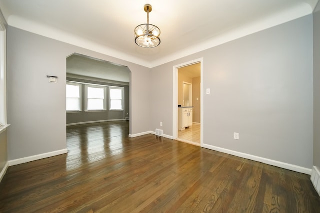 spare room with an inviting chandelier and dark wood-type flooring