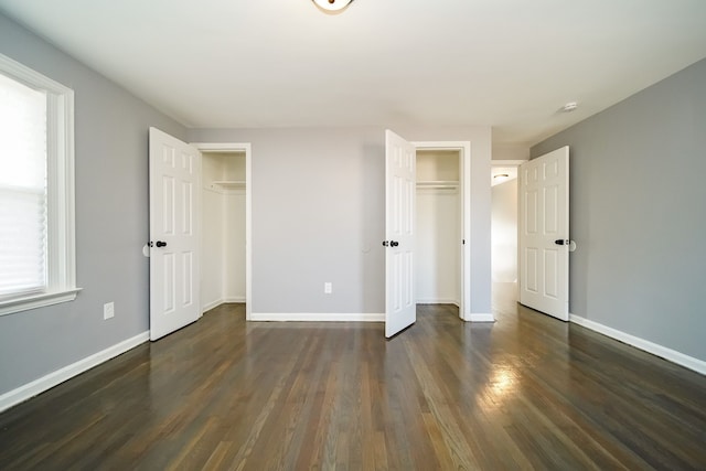 unfurnished bedroom featuring dark hardwood / wood-style flooring and multiple closets