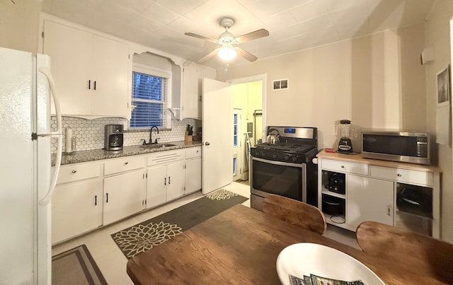 kitchen featuring appliances with stainless steel finishes, tasteful backsplash, white cabinetry, sink, and ceiling fan