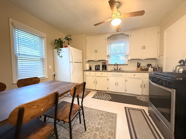 kitchen featuring white cabinetry, sink, stainless steel gas range, and white fridge