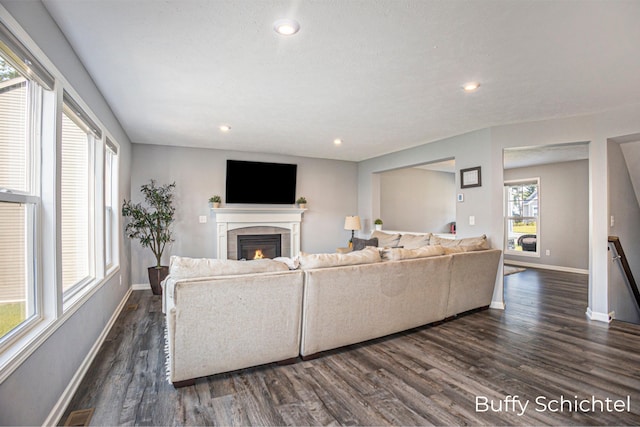 living room featuring a tile fireplace and dark wood-type flooring