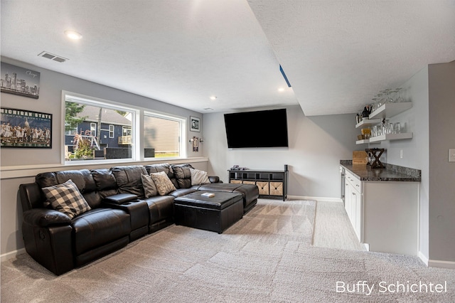 living room with light carpet, bar area, and a textured ceiling