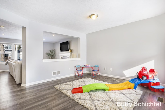 rec room featuring dark wood-type flooring and a textured ceiling