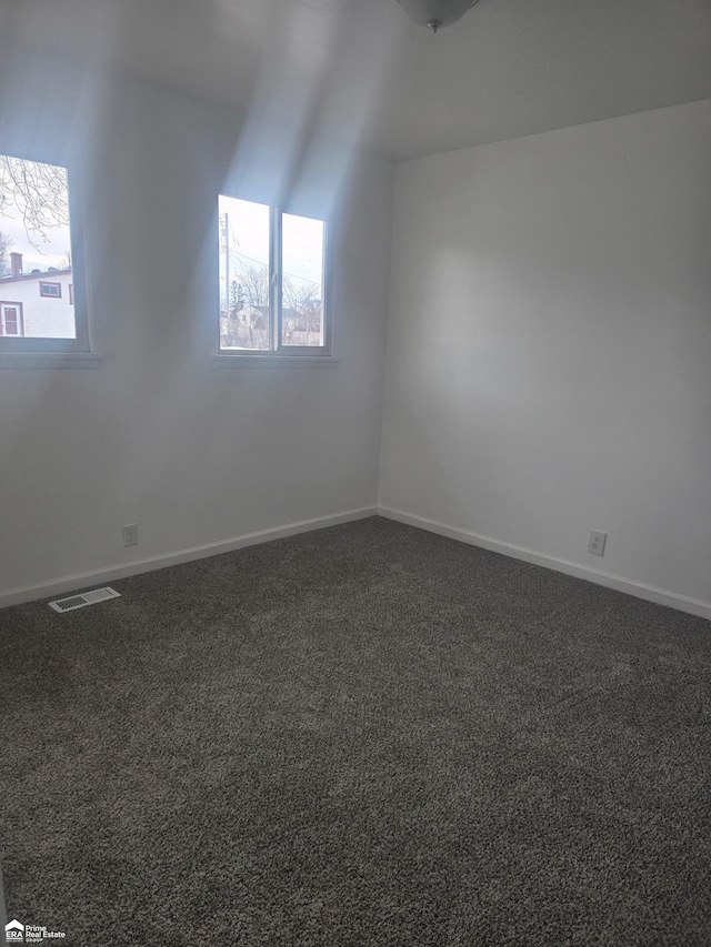 spare room with dark carpet and plenty of natural light