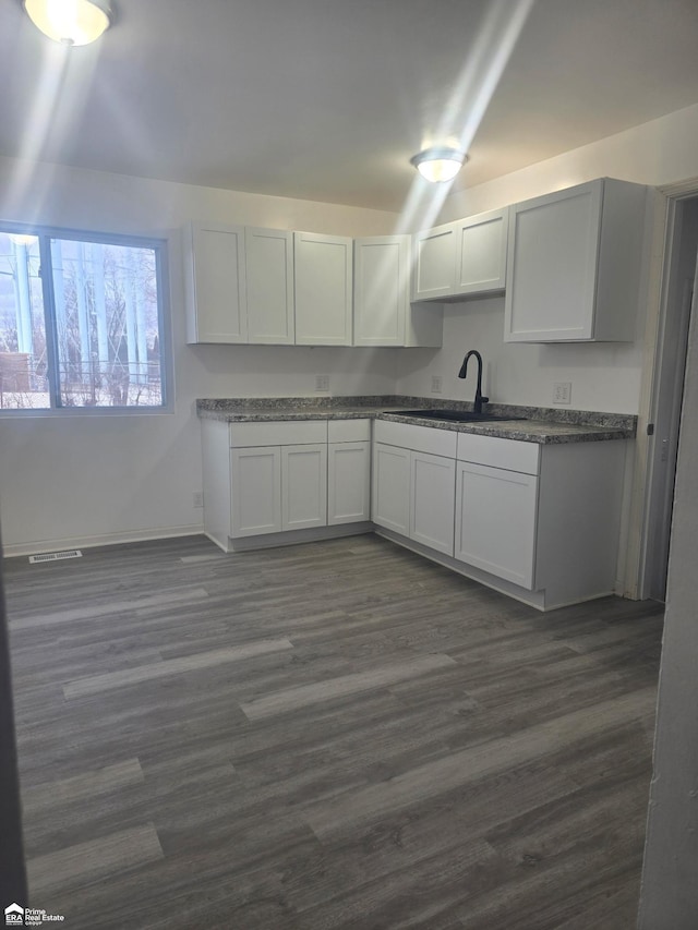 kitchen with white cabinetry, sink, and dark wood-type flooring