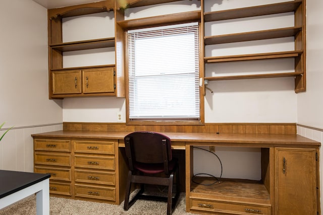 carpeted home office featuring built in desk and wood walls