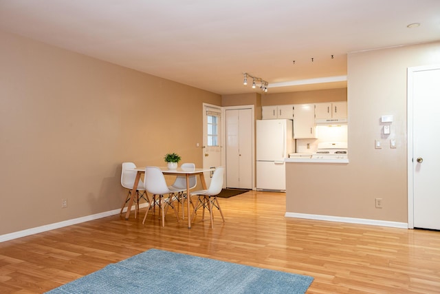 dining space featuring rail lighting and light hardwood / wood-style flooring