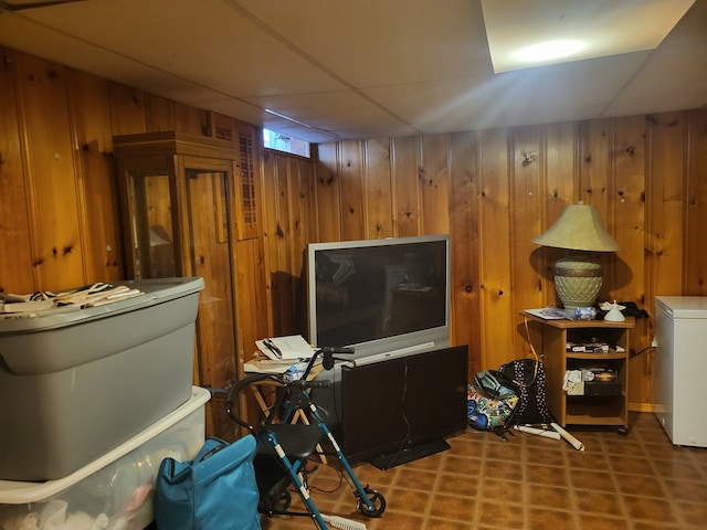 interior space featuring a paneled ceiling and wood walls