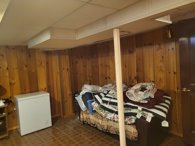 bedroom featuring fridge and wood walls