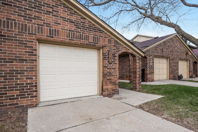 exterior space with brick siding, an attached garage, and driveway