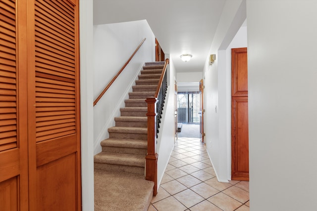 stairway with carpet flooring and tile patterned flooring