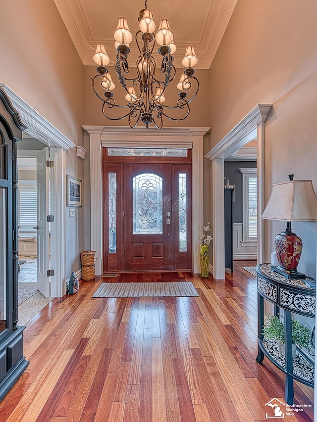 foyer featuring wood-type flooring, ornamental molding, and a towering ceiling