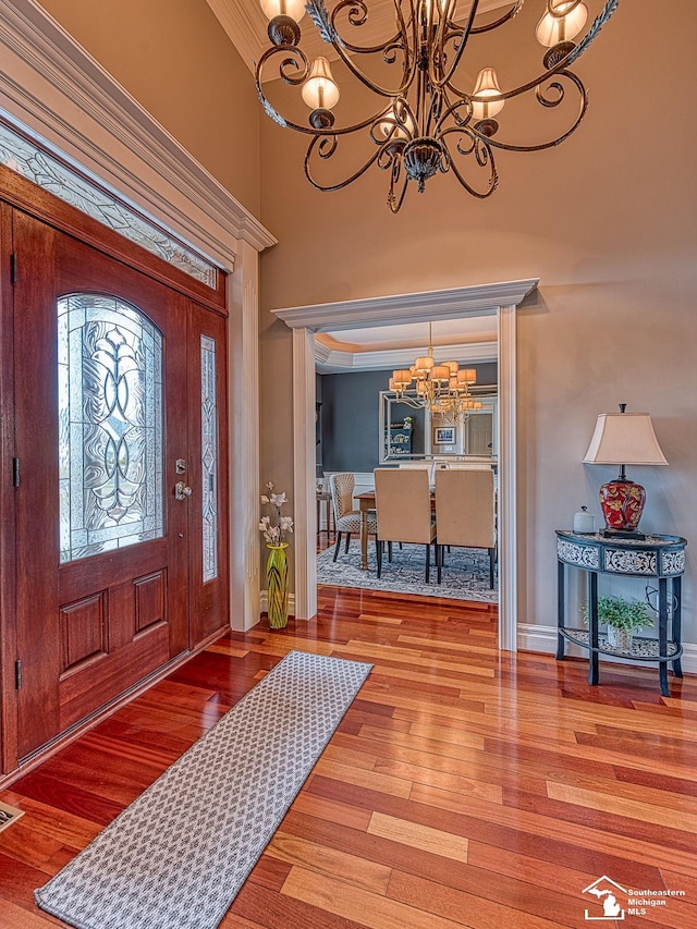 foyer entrance with a high ceiling, hardwood / wood-style floors, and a notable chandelier