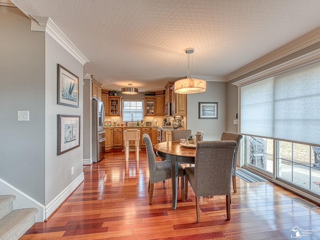 dining space featuring hardwood / wood-style floors, ornamental molding, sink, and a textured ceiling