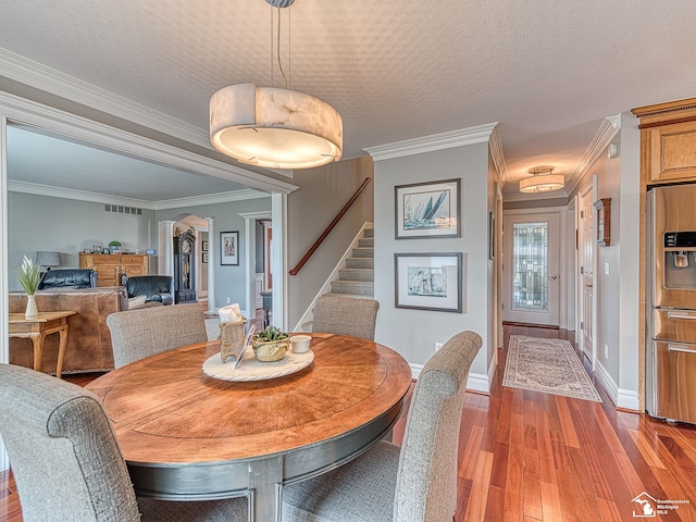 dining space with crown molding, a textured ceiling, and light hardwood / wood-style floors