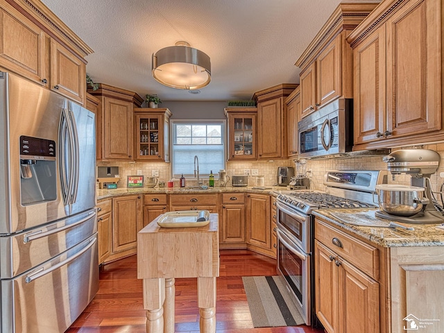 kitchen with stainless steel appliances, dark hardwood / wood-style floors, a center island, and sink